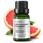 Flacone AMYRON di olio essenziale di pompelmo 15 ml davanti a pompelmi rosa tagliati